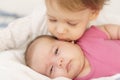 Two children lying on the bed hugging indoors.Older brother kisses, aying down ,cuddling ,hugging and holding the hand Royalty Free Stock Photo