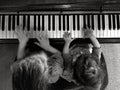 Two children play music on piano