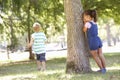 Two Children Playing Hide And Seek In Park