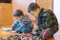 Two children playing with lots of colorful plastic blocks constructor sitting on a floor indoor. Two little brothers play Royalty Free Stock Photo