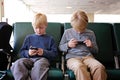 Two Children PLaying on their Cell Phones while Waiting for Airplane at the Airport Royalty Free Stock Photo