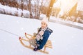 Two children ride on wooden retro sled on sunny winter day. Active winter outdoors games. Winter activities for kids Royalty Free Stock Photo