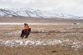 Two children riding a horse, view from the back. A yurt on a snowy plateau, nomadic life in Mongolia. A wide expanse