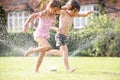 Two Children Running Through Garden Sprinkler Royalty Free Stock Photo