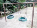 Two children`s swings made of a car wheel painted with blue paint and hanging on chains on iron pipes Royalty Free Stock Photo