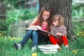 Two children sisters reading the book in the summer park.