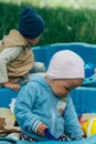 Two children sit in the sandbox and play with shovels, rakes, toys Royalty Free Stock Photo