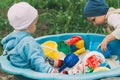 Two children sit in the sandbox and play with shovels, rakes, toys Royalty Free Stock Photo
