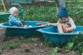 Two children sit in the sandbox and play with shovels, rakes, toys Royalty Free Stock Photo