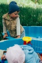 Two children sit in the sandbox and play with shovels, rakes, toys Royalty Free Stock Photo