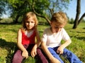 Two children are sitting in a meadow and bored with idleness. A girl of 6 years old and a boy of 7 years old are playing outdoors Royalty Free Stock Photo