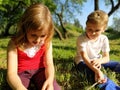 Two children are sitting in a meadow and bored with idleness. A girl of 6 years old and a boy of 7 years old are playing outdoors Royalty Free Stock Photo