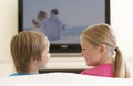 Two Children Watching Widescreen TV At Home