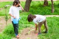 Two children are watering plants in a garden