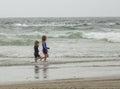 Two children, a young boy and a young girl, running through shallow waves and playing at the beach Royalty Free Stock Photo