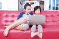 Two childs using laptop on couch at home Royalty Free Stock Photo
