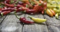 Two chilli peppers in front of large group of peppers on wooden Royalty Free Stock Photo