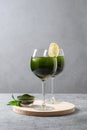 Two chlorella beverage with lemon in glass on gray background