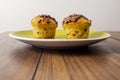 Two chocolate chip muffins on a yellow plate and wooden table . Copy space. Premium quality bakery product Royalty Free Stock Photo