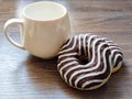 two chocolate donuts and a white cup on a wooden table Royalty Free Stock Photo