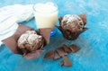 Two chocolate muffins, black chocolate and a glass of milk on a blue background