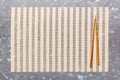 Two chopsticks and bamboo mat on cement background. Top view, copy space Royalty Free Stock Photo