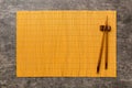 Two chopsticks and bamboo mat on cement background. Top view, copy space Royalty Free Stock Photo