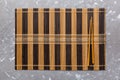 Two chopsticks and bamboo mat on cement background. Top view, copy space Royalty Free Stock Photo
