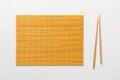 Two chopsticks and bamboo mat on cement background. Top view, copy space Royalty Free Stock Photo