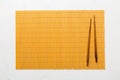 Two chopsticks and bamboo mat on cement background. Top view, copy space Royalty Free Stock Photo