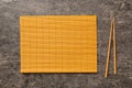 Two chopsticks and bamboo mat on cement background. Top view, copy space Royalty Free Stock Photo