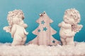 Two Christmas baby angels statuettes on snow with Christmas tree Royalty Free Stock Photo