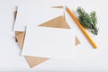 Two Christmas blank greeting cards mock-up. Craft envelopes, pine twig, pencil and card template with empty space for text Royalty Free Stock Photo