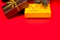 Two Christmas gifts - brown and yellow, tied with ribbons under the Christmas tree on a red background. 2021. Royalty Free Stock Photo