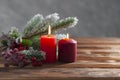 Two christmas red burning candles and branch of christmas tree on the wooden background Winter holiday xmas and new year Royalty Free Stock Photo