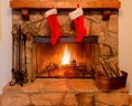 Two Christmas Stockings On The Mantle Of A Stone Fireplace With A Warm Fire.