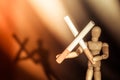 Two cigarettes in cross form holding by wooden man figure with blurred shadow on background