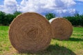 Two Circular bales of straw in a meadow under a blue sky Royalty Free Stock Photo