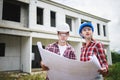 Two Civil Engineers, field engineers, foreman, owner standing in the construction site project in the background Royalty Free Stock Photo