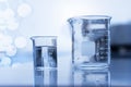 Two clear beaker with water in chemical science laboratory research background