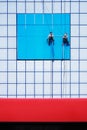 Two climbers on a blue office building hang a banner Royalty Free Stock Photo