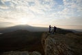 Two climbers standing on summit above clouds in the mountains holding hands. Silhouettes of hikers celebrating ascent on Royalty Free Stock Photo