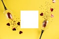 Two clinking wine glasses poured out red heart confetti on yellow color paper background. Minimal style. Royalty Free Stock Photo