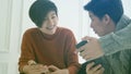 Two close Asian friends sharing application and information on mobile phone