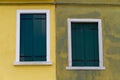 Two closed green windows on a yellow wall Royalty Free Stock Photo