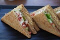 Two club sandwiches placed on a black plate at a restaurant. Close-up photo of a club sandwich. Sandwich with prosciutto,