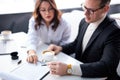 two co-workers sit behind table talking, using clipboard document, discussing Royalty Free Stock Photo