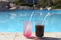 Two cocktail glasses by a blue water swimming pool. summer vacation Royalty Free Stock Photo