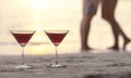 Two cocktails on the beach with couple kissing in background Royalty Free Stock Photo