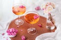 Two cocktails decorated with flowers on a white table next to the window and a vase with roses in the background. Royalty Free Stock Photo
